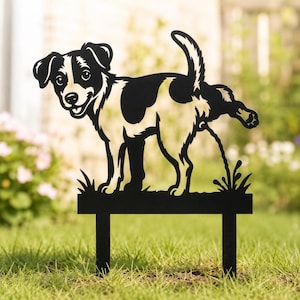 Puede incluir: Una silueta de estaca de jardín de metal negro de un perro pequeño con manchas en el cuerpo. El perro está representado sobre una base rectangular con dos puntas, con una pata levantada y un fino chorro de líquido hacia el césped.