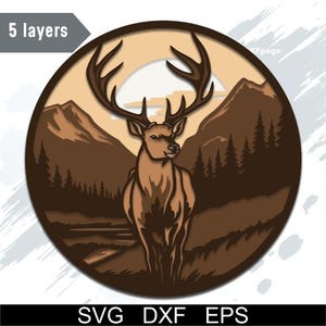 May include: A layered, circular design featuring a deer with large antlers set against a mountain and forest backdrop. The color palette includes shades of brown and tan, with the text "5 layers" in the upper left corner and "SVG DXF EPS" at the bottom.