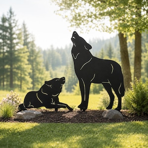Peut inclure: Deux silhouettes de loups en métal noir placées sur un lit de paillis. Un loup est debout et hurle la tête tournée vers le haut, tandis que le second loup est allongé sur le sol, la tête également tournée vers le haut dans une pose de hurlement.
