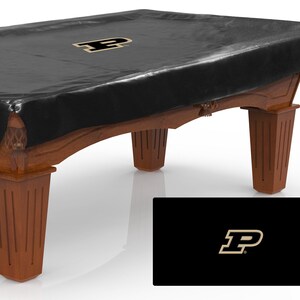 May include: Black pool table cover with a gold "P" logo. The cover is made of a durable, water-resistant material and is designed to protect your pool table from dust, dirt, and spills.