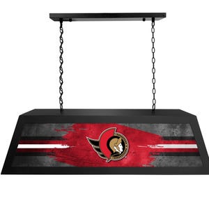 May include: Black light fixture with a red, white, and gray design featuring a hockey team logo. The logo is a red and gold winged helmet with a warrior's face.