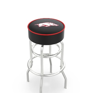 May include: A black bar stool with a red trim and a red and white Arkansas Razorbacks logo on the seat.