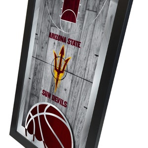 May include: A framed print of a basketball court with a maroon basketball and the Arizona State Sun Devils logo. The logo is a gold spear with a red and yellow background. The text "BASKETBALL" is at the top of the print.