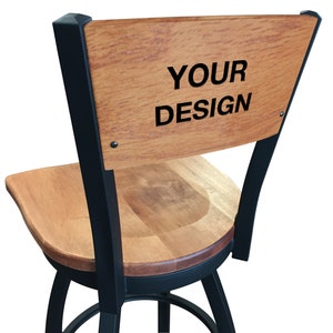 May include: A black metal swivel bar stool with a wood seat and back. The back of the stool has the text "YOUR DESIGN" engraved on it.