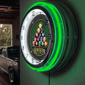 May include: A round wall clock featuring a bright green neon light ring and a black face with white numbers. The center displays a triangular rack of colorful billiard balls and the text RACK'EM in yellow script with a black outline.