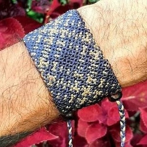 Puede incluir: Un brazalete tejido azul y dorado con un borla. El brazalete está atado alrededor de la muñeca de una persona.