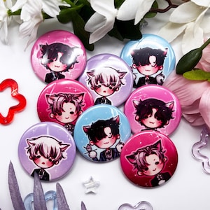 Op de afbeelding: Een verzameling van zeven ronde buttons met speldsluiting, voorzien van chibi-stijl anime-personages met kattenoren. De buttons hebben diverse achtergrondkleuren zoals roze, lichtblauw en lavendel, met sprankelende accenten en donkerharige figuren.