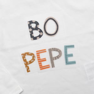 Könnte beinhalten: Weißes Langarmshirt mit den Worten "BO PEPE" in bunten, gemusterten Buchstaben.