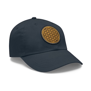 Puede incluir: Una gorra de béisbol azul marino con un parche de diseño de flor de la vida amarillo en la parte delantera.
