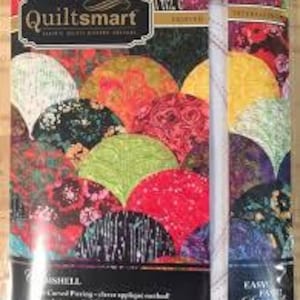 Könnte beinhalten: Eine QuiltSmart Vlieseinlage-Packung mit Druck für Clamshell-Quiltmuster. Die Verpackung zeigt eine bunte Anordnung überlappender kreisförmiger Formen in Rot, Gelb, Grün, Lila und Schwarz, mit dem sichtbaren Text QuiltSmart und Clamshell.