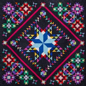May include: A colorful quilt with a large, blue, star-shaped design in the center. The quilt is made up of many different colored triangles and squares, and it is surrounded by a border of pink and black.