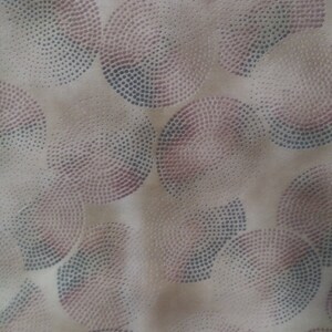 May include: A fabric with a repeating pattern of semi-circles composed of small dots. The dots are in shades of purple and gray, set against a beige background. The design creates a textured, abstract appearance.