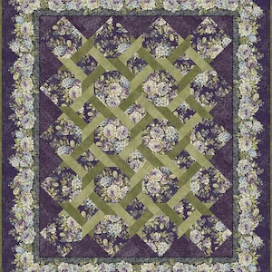 Può includere: Una trapunta rettangolare con un motivo centrale di quadrati di tessuto floreale viola scuro sovrapposti a un reticolo di strisce di tessuto verde oliva. La trapunta è incorniciata da un ampio bordo di grappoli floreali bianchi, viola e verdi.