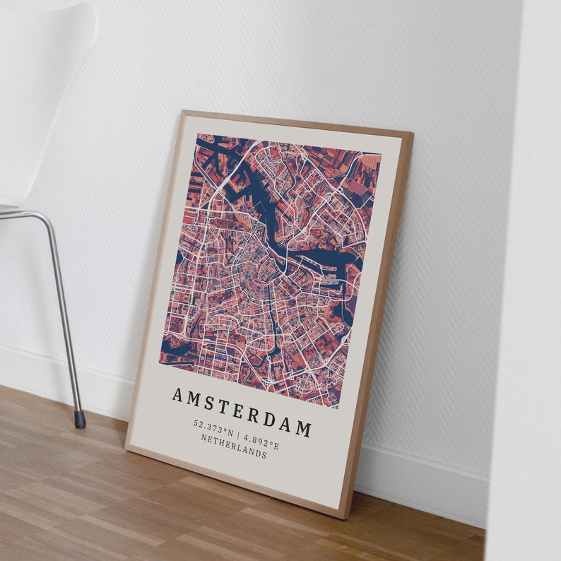 May include: A framed map print of Amsterdam, Netherlands. The map is in a muted red and blue color scheme. The city name and coordinates are printed at the bottom of the map.