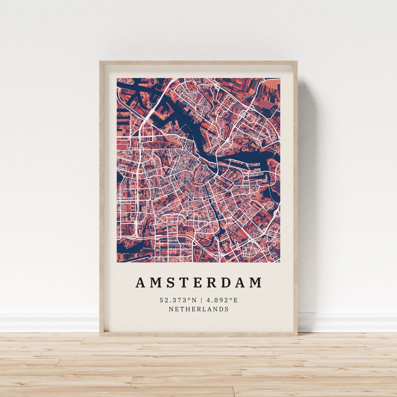 May include: A framed map of Amsterdam, Netherlands, with a red and blue color scheme. The map shows the city's canals and streets. The text "AMSTERDAM" is printed in black at the bottom of the map, along with the coordinates "52.3733&deg;N | 4.8922&deg;E".