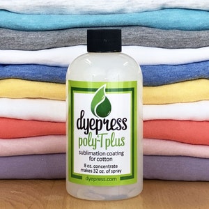 Pu&ograve; includere: Una bottiglia di plastica trasparente di rivestimento di sublimazione dye press poly-Tplus per cotone. La bottiglia &egrave; etichettata con il nome del prodotto, un logo di foglia verde e il testo "8 oz. concentrate makes 32 oz. of spray" e "dyepress.com". La bottiglia &egrave; appoggiata su una superficie di legno davanti a una pila di magliette piegate in vari colori.