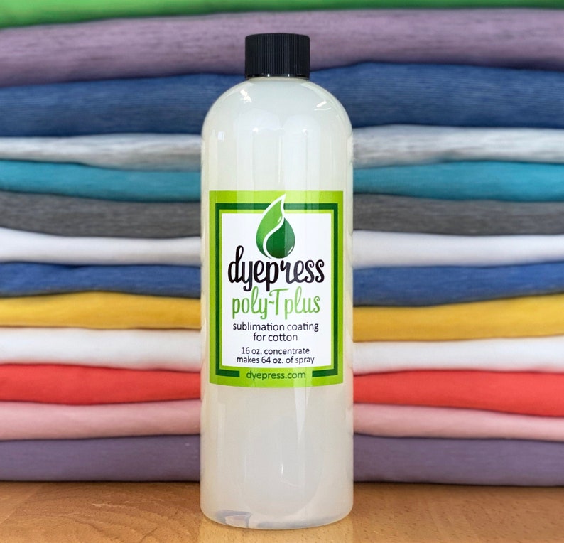 May include: A clear plastic bottle with a black cap and a green label that says "dyepress poly-Tplus sublimation coating for cotton 16 oz. concentrate makes 64 oz. of spray dyepress.com". The bottle is in front of a stack of colorful t-shirts.
