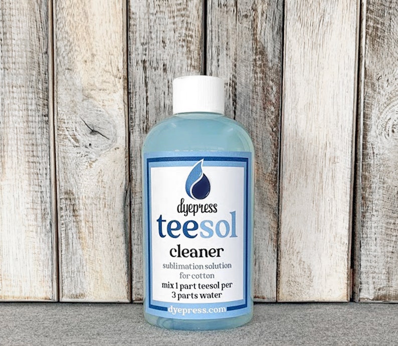May include: A blue bottle of dye press teesol cleaner for sublimation on cotton. The bottle has a white label with the text "dyepress teesol cleaner sublimation solution for cotton mix 1 part teesol per 3 parts water dyepress.com".