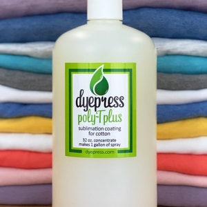 May include: A clear plastic bottle with a white cap, labeled "dyepress poly-Tplus sublimation coating for cotton 32 oz. concentrate makes 1 gallon of spray dyepress.com". The bottle is in front of a stack of colorful t-shirts.