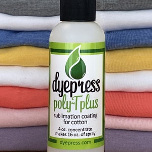 May include: A clear plastic bottle with a black cap labeled "dyepress poly-Tplus sublimation coating for cotton 4 oz. concentrate makes 16 oz. of spray dyepress.com". The bottle is sitting on a wooden surface in front of a stack of folded t-shirts in various colors.