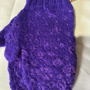 May include: Purple knitted mittens with a textured pattern. The mittens are made with a soft, fuzzy yarn.