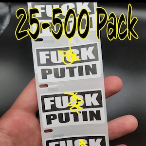 Puede incluir: Una tira de pegatinas blancas con las palabras "FUCK PUTIN" en letras mayúsculas negras en negrita. El texto "25-500 Pack" está escrito en letras negras estilizadas en la parte superior. Las pegatinas se sostienen en una mano.