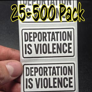 以下が含まれることがあります： 「DEPORTATION IS VIOLENCE」のテキストが黒い太字で白地に印刷された長方形のステッカーのロール。黒い縁取りがあり、テキストは中央に配置されています。ステッカーロールの上部には「25-500 Pack」と書かれています。