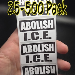 以下が含まれることがあります： 「ABOLISH ICE」というテキストが5回繰り返された黒と白のステッカーのシート。ステッカーはロール状になっており、「25-500 Pack」とラベル付けされています。
