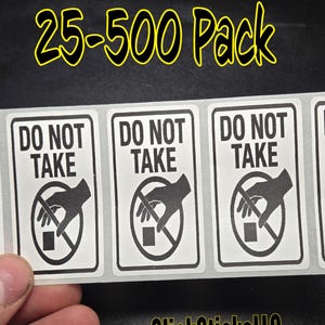 Op de afbeelding: Een vel witte stickers met zwarte tekst en afbeeldingen. Elke sticker leest "DO NOT TAKE" boven een afbeelding van een hand die naar een klein vierkant grijpt, doorgestreept met een rode cirkel. De tekst "25-500 Pack" is geel.