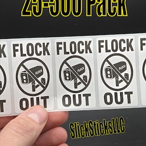 May include: A hand holding a strip of white stickers with a black and white graphic of a security camera with a line through it. The text "FLOCK OUT" is below the graphic. The text "25-500 Pack" is at the top.
