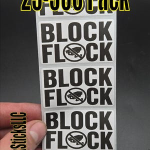 Może przedstawiać: Pionowy pasek prostokątnych białych naklejek z czarnym napisem BLOCK FLOCK oraz grafiką kamery bezpieczeństwa wewnątrz koła zakazu. Na górze paska znajduje się napis 25-500 Pack dużymi żółtymi i czarnymi literami.
