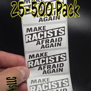 May include: A sheet of white rectangular stickers with the text "MAKE RACISTS AFRAID AGAIN" in bold black letters. The text "25-500 Pack" is in yellow and black. The brand name "SlickSticksLLC" is printed vertically on the left side.
