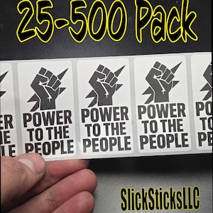 May include: A sheet of stickers with a black fist graphic and the words "POWER TO THE PEOPLE" in white. The text "25-500 Pack" is in yellow. The brand name "SlickSticksLLC" is also in yellow.