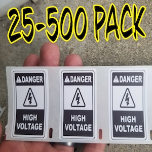 May include: Three black and white warning labels with the text "DANGER HIGH VOLTAGE" and a lightning bolt symbol. The labels are on a sheet of white paper. The text "25-500 PACK" is written in yellow and black at the top of the image.