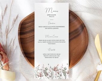 May include: A wedding menu card with a floral design. The menu includes a salad, salmon with lemon butter sauce, and dessert options. The text on the card reads "Menu", "John & Jane", "06.23.23", "Soup", "Mixed Greens Salad with Strawberries and Sliced Almonds", "Main Course", "Herb Crushed Salmon with Lemon Butter Sauce, Crispy Mashed Potatoes & Roasted Vegetables", "Desserts", "Apple Tart with Ice Cream", "Molten Chocolate Cake", "Fresh Fruit & Cream".