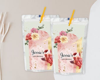 May include: Two clear plastic juice pouches with floral designs and gold accents. The pouches have a straw attached and say "Jessie's First Birthday" on the front.