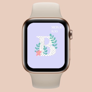 May include: A gold Apple Watch with a white band displays a watch face with a large letter "B" with black polka dots and green leaves. The time is 8:30 and the date is MON 10.