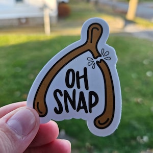 May include: White sticker with a brown pretzel shape and the text "OH SNAP" in black.