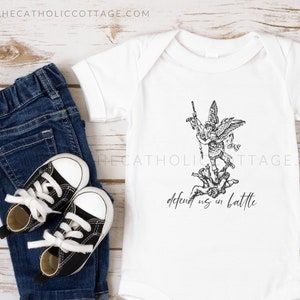 May include: White baby onesie with a black and white illustration of an angel with a sword, and the text "defend us in battle".