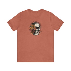 May include: A heather red t-shirt with a skull graphic. The skull is surrounded by flowers and the text "and to dust you shall return".