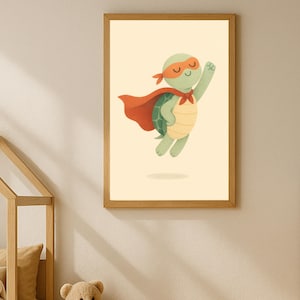 Op de afbeelding: Een ingelijste print met een cartoon schildpad als superheld. De schildpad is groen met een gele schild, draagt een rood masker en cape. Het kunstwerk staat tegen een crèmekleurige achtergrond, ingelijst in licht hout, voor een kinderkamer.