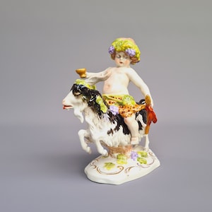 Porcelain figurine of baby Bacchus riding a goat is full of joy, movement and a touch of naughtiness ++