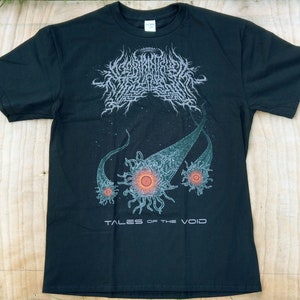 May include: Black t-shirt with a band logo and graphic design. The logo is in a white font and says "Worm Ouroboros". The graphic design is of a black and white space scene with three glowing orbs. The text "Tales of the Void" is printed below the graphic.
