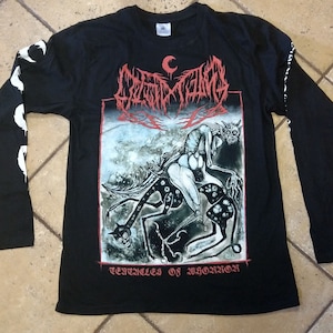 May include: Black long-sleeved t-shirt with a white and black graphic print of a creature with a horned head riding another creature. The text "CULT OF FIRE" and "TERRIFIED OF HORROR" are printed on the shirt.
