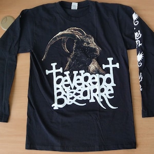 May include: Black long-sleeved t-shirt with a white graphic of a goat's head with horns and the text "behemoth beware" printed on the front. The sleeves have a white graphic of a stylized dragon.