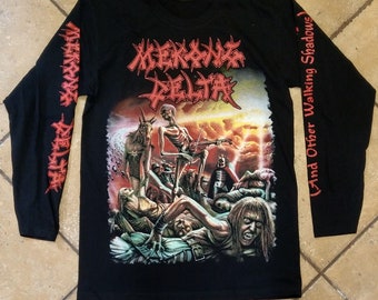 Könnte beinhalten: Schwarzes Langarm-T-Shirt mit einem Grafikdruck einer skelettartigen Figur, die Gitarre spielt vor einem feurigen Hintergrund. Der Text "MORKBORG DELTA" ist in Rot auf der Vorderseite des Shirts gedruckt. Der Text "(And Other Walking Shadows)" ist in Rot auf dem rechten Ärmel gedruckt.