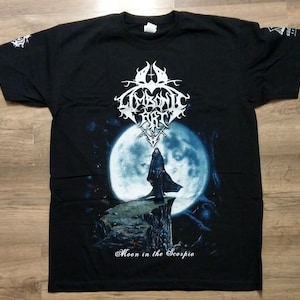 May include: Black t-shirt featuring a white graphic of a band called "Limbonic Art" and a full moon with a figure standing on a cliff. The text "Moon in the Scorpio" is at the bottom of the graphic.