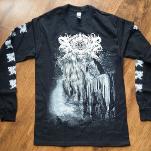 Op de afbeelding: Zwart longsleeve shirt met een witte grafische print van een grot met stalactieten en stalagmieten. De bandnaam "Darkthrone" is in wit op de voorkant van het shirt gedrukt. De mouwen hebben een witte grafische print van een herhalend patroon.