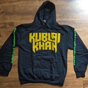 May include: Black hooded sweatshirt with yellow "KUBLAI KHAN" text on the front and green stripes on the sleeves.