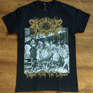Puede incluir: Camiseta negra con un estampado gráfico dorado de un logotipo de banda y una imagen en blanco y negro de un grupo de personas. El texto "Exorcising the Dimensional" está impreso debajo de la imagen.